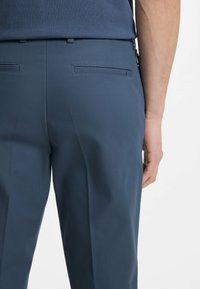 Granatowe, dopasowane spodnie o gładkiej fakturze, z tylnymi kieszeniami i czystym krojem, zaprojektowane dla nowoczesnego dopasowania.