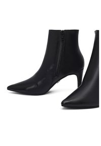 Zwarte leren enkellaarsjes met puntige tenen, een ritssluiting aan de zijkant en slanke midhoge naaldhakjes op een witte achtergrond.