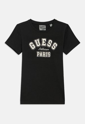 Sort T-shirt lavet af bomuld med rund halsudskæring og korte ærmer. Dekorativ tekst "GUESS Athleisure PARIS" i hvid med nitte detaljer.