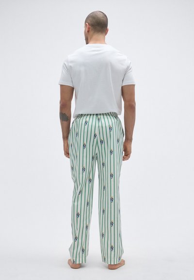 Bijela majica kratkih rukava uparen s pidžama hlačama u zeleno-bijele pruge s razigranim uzorkom malih likova. Hlače imaju elastični pojas.