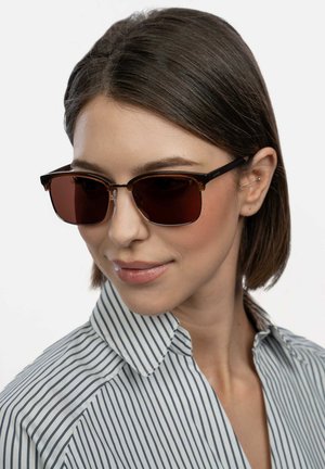 Brown rectangular sunglasses with dark lenses, light brown and black frames, worn by a person in a striped collared shirt.
