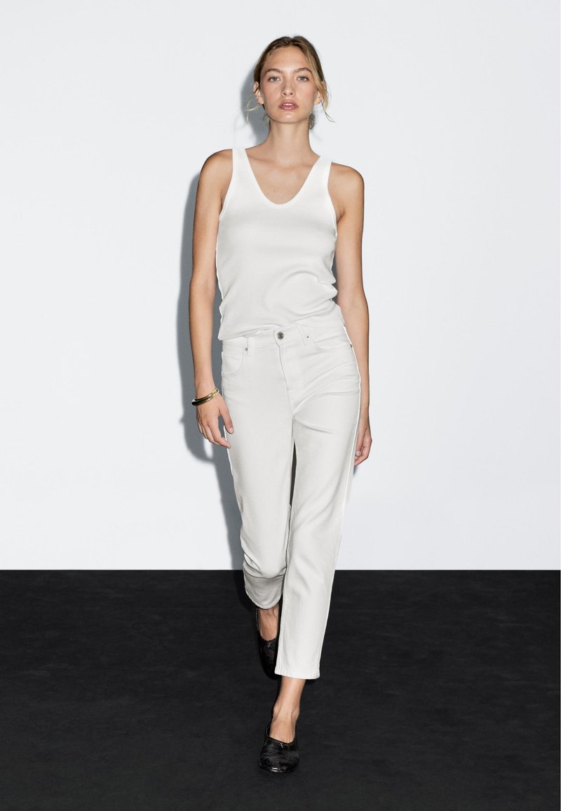 Ljusbeige linne matchat med ljusbeiga rakbenbyxor, med en slät yta och minimalistisk design, fulländat med svarta skor.