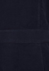 Primo piano di un tessuto a coste navy blu scuro con dettagli di cucitura orizzontale e verticale.