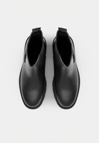 Sorte ankelstøvler i skinn med runde tær og elastiske sidepaneler, sett ovenfra på hvit bakgrunn.