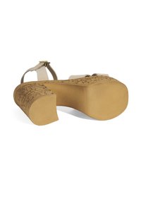 Sandale à plateforme beige avec un talon en liège texturé et des brides lisses de couleur claire ; la semelle en caoutchouc présente une texture pour une meilleure adhérence.