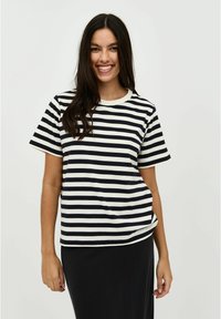 Striped short-sleeve t-shirt in navy and cream, featuring a round neckline and a relaxed fit, paired with a black skirt.