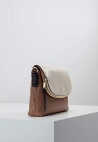 Brown leather handbag with a textured light gray flap, gold zipper, and black accent strap. Compact design with a sleek, modern shape.
