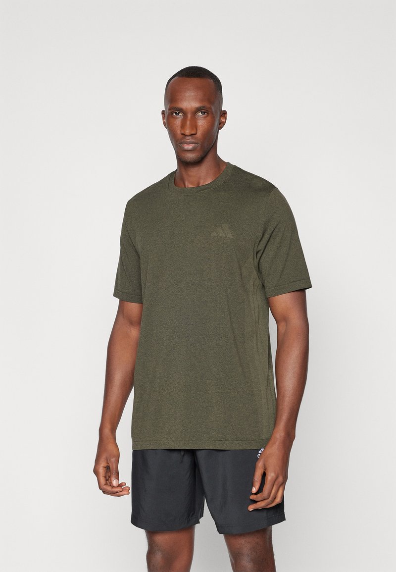 Camiseta deportiva verde oliva hecha de tejido texturizado, con mangas cortas y cuello redondo, combinada con pantalones cortos negros.