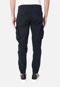 Pantaloni cargo blu navy con polsini elasticizzati, tasche laterali e un tessuto resistente. Progettati con un taglio classico e dettagli di cucitura minimi.