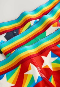 Šarena donje rublje s crvenom podlogom, koja prikazuje višebojne zvjezdice i trokutaste uzorke. Elastična traka u kišobranu boja s kontrastnim šavovima.