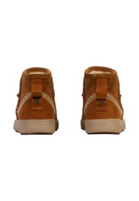 Bottes chevilles en suède marron avec des coutures blanches, des panneaux latéraux texturés et une languette arrière en boucle. Doublure intérieure douce visible en haut.