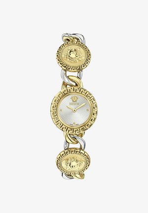 Ure i guld- og sølvtoner med rundt urværk, sølvstribet skive, græsk nøglemønster og Medusa-myntedetaljer på armbåndet.