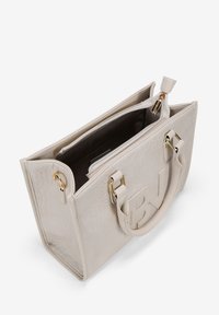 Bolso de mano de cuero beige con un acabado texturizado, acentos de hardware dorado, asas superiores y un bolsillo interior con cremallera. Presenta un detalle con el logo.