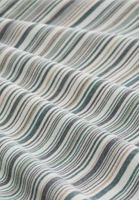 Tissu multicolore présentant des rayures ondulées en teal, marron, gris et crème. La texture semble douce et lisse, avec un design léger.