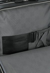 Intérieur en tissu gris d'un sac, comprenant un emplacements pour cartes en cuir noir texturé et une poche élastique, avec un motif subtil.