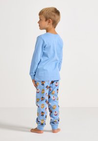 Blue long-sleeve top and blue pajama pants with cartoon character patterns, soft cotton fabric, relaxed fit, and elastic cuffs at the ankles.