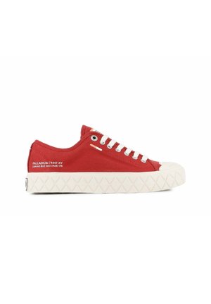 Rode lage canvas sneaker met witte rubberen zool, witte veters en tekstdetail aan de zijkant op een schone witte achtergrond.
