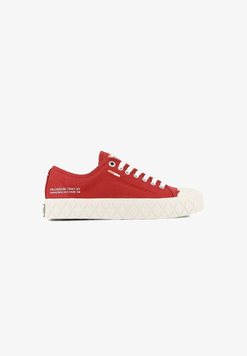 Baskets rouges basses en toile avec semelle en caoutchouc blanche, lacets blancs et détail de texte sur le côté sur fond blanc propre.