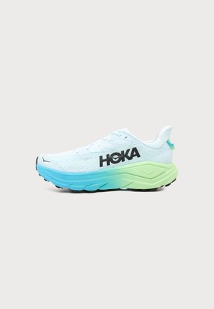 Λευκό τρέξιμο παπούτσι Hoka με σόλα σε διαβάθμιση από μπλε σε πράσινο και μαύρο λογότυπο HOKA στο πλάι, εμφανίζεται σε απλό ανοιχτό φόντο.