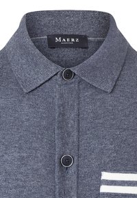 Marinblå stickad polo med spetsig krage, knäppning fram och vit randig detalj på bröstfickan. Märke: Maerz.