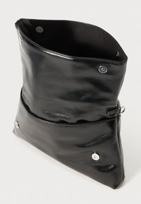 Borsa in pelle nera con una texture liscia, forma triangolare, chiusure a scatto e una parte superiore leggermente aperta. Include una tasca frontale con cerniera.