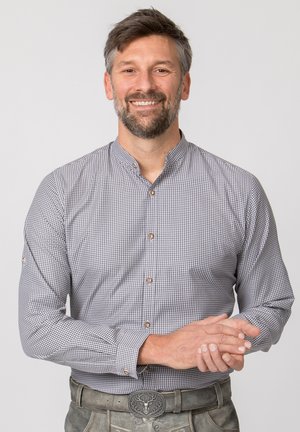 Hemd mit Knopfleiste in kariertem Muster, grau und weiß, mit Stehkragen. Ausgestattet mit Holzknöpfen und hochgekrempelten Ärmeln. Kombiniert mit grauer Hose.