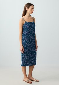Ärmelloses Midikleid aus dunkelblauem Stoff mit floralem Muster in helllila. Verfügt über verstellbare Träger und einen ausgestellten Saum.