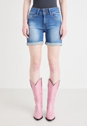 Denim shorts in faded blue with rolled cuffs; paired with tall pink cowboy boots featuring embossed floral details and pointed toes.