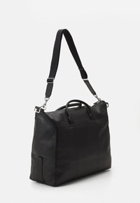 Black leather duffel bag with a structured shape, two top handles, and a detachable shoulder strap. Smooth texture, minimalistic design.