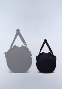 Rund marinblå väska av tyg, med justerbara remmar, dragkedja och svarta detaljer. Två storlekar visas, en större och en mindre.