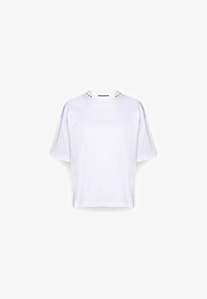 Weißes oversized T-Shirt mit kurzen Ärmeln, lockerem Sitz und dekorativen silbernen Nieten entlang des Rundhalsausschnitts.