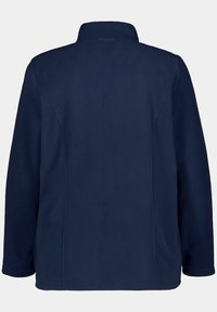 Giacca in pile blu navy con colletto alto, taglio dritto, maniche lunghe e senza chiusure o decorazioni visibili. Tessuto semplice e testurizzato.
