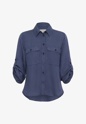 Camicia blu navy a bottoni in tessuto leggero, con maniche arrotolate, due tasche sul petto e dettagli a bottoni neri. L'orlo è curvo.