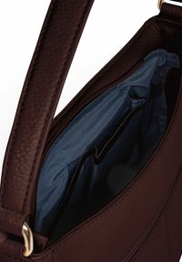 Borsa a mano in pelle bordeaux con una texture a granuli. L'interno presenta una fodera blu e tasche organizzative. Accenti in metallo dorato.