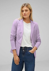 Light lavender blazer with a tailored design, structured shoulders, and two front pockets, worn over a white shirt and dark blue jeans.