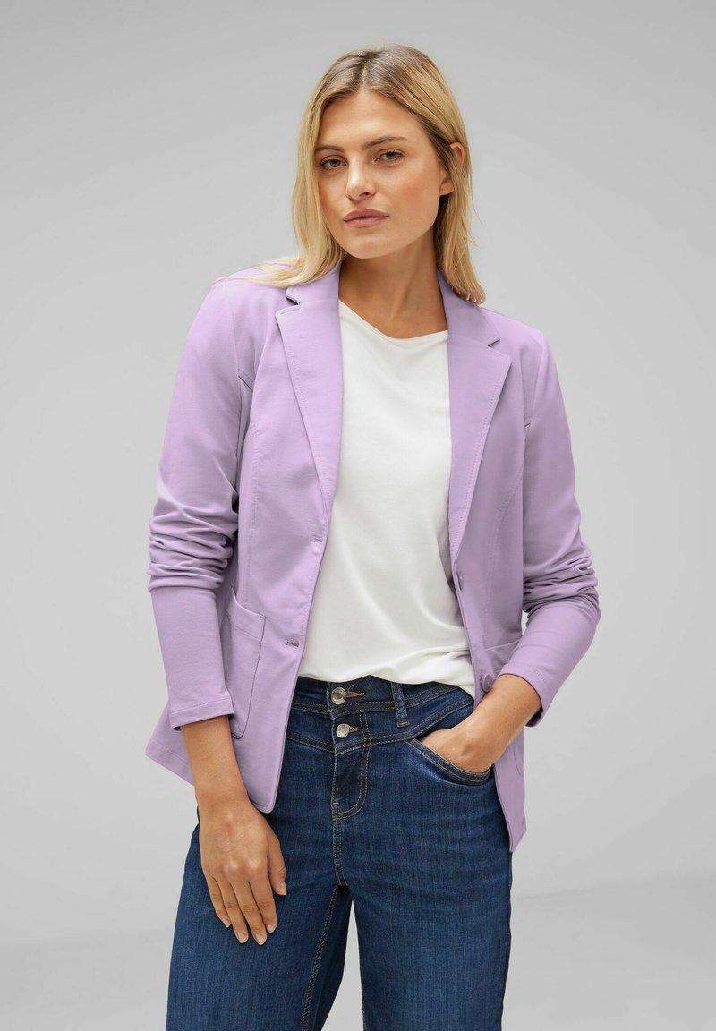 Light lavender blazer with a tailored design, structured shoulders, and two front pockets, worn over a white shirt and dark blue jeans.
