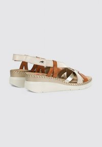 Sandalias de cuña con tiras en beige, marrón y metálicas, con un detalle de costura y una suela blanca para mayor altura.