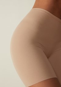 Beige stretch shorts met een soepele textuur, elastische tailleband en een figuurvormend ontwerp, geknipt op het midden van de dij voor bedekking en comfort.