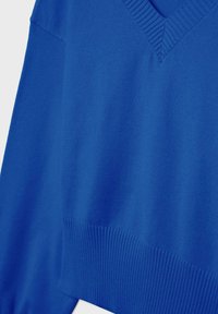 Pull bleu en maille avec un col en V, doté de poignets et d'un ourlet côtelés. Texture lisse, tissu de poids moyen, coupe décontractée.