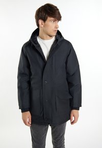 Parka nera con chiusura a zip e bottoni, dotata di cappuccio, due tasche frontali e polsini a costine. Tessuto morbido con finitura opaca.