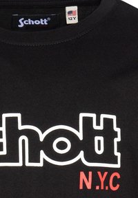 Camiseta de algodón negra con un audaz logo blanco de "Schott" y el texto rojo "N.Y.C". Cuello redondo con un ajuste estándar. Etiqueta de talla: 12 años.