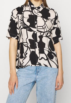 Short-sleeve button-up shirt with black and beige abstract floral pattern worn with light blue jeans.