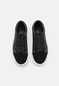 Black sneakers with a leopard print pattern, suede material, flat shoelaces, white rubber sole, and padded collar for comfort.