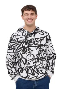 Felpa bianca con motivi in stile graffiti neri, inclusi testi e faccine sorridenti. Ha una tasca frontale e un cappuccio con cordini.