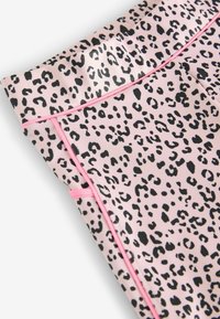 Leggings en imprimé léopard rose clair avec des taches noires. Dotés d'un piping contrastant rose le long des coutures. Matériau lisse et extensible.