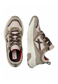 Zapatillas con una parte superior de ante beige y marrón, que cuentan con suelas de goma blancas y cordones oscuros. Logo distintivo de estrella marrón en los laterales.