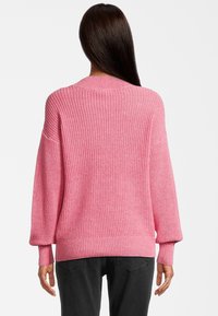 Różowy sweter z dzianiny o fakturowanym splocie, z ribbrowymi mankietami i dołem, oraz okrągłym dekoltem. Krój jest luźny i nieco oversize.