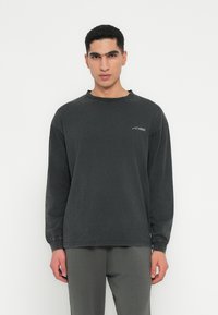 Długi rękaw, ciemnoszary sweatshirt wykonany z miękkiej mieszanki bawełny, z okrągłym dekoltem i subtelnym logo na piersi.