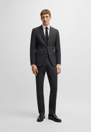 Dunkelgrau Anzug mit maßgeschneiderter Passform, einreihiger Jacke, Reverskragen und passender Hose; kombiniert mit einem weißen Hemd und einer schwarzen Krawatte.