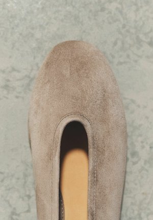 Üksik beežist seemisnahast libistatav king ümarate ninadega hallil tekstuuriga pinnal.